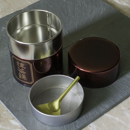 Buy Online - Matcha strainer tin. This airtight storage tin has an integrated mesh strainer and strainer spoon to remove clumps from matcha. All in a beautiful presentation.